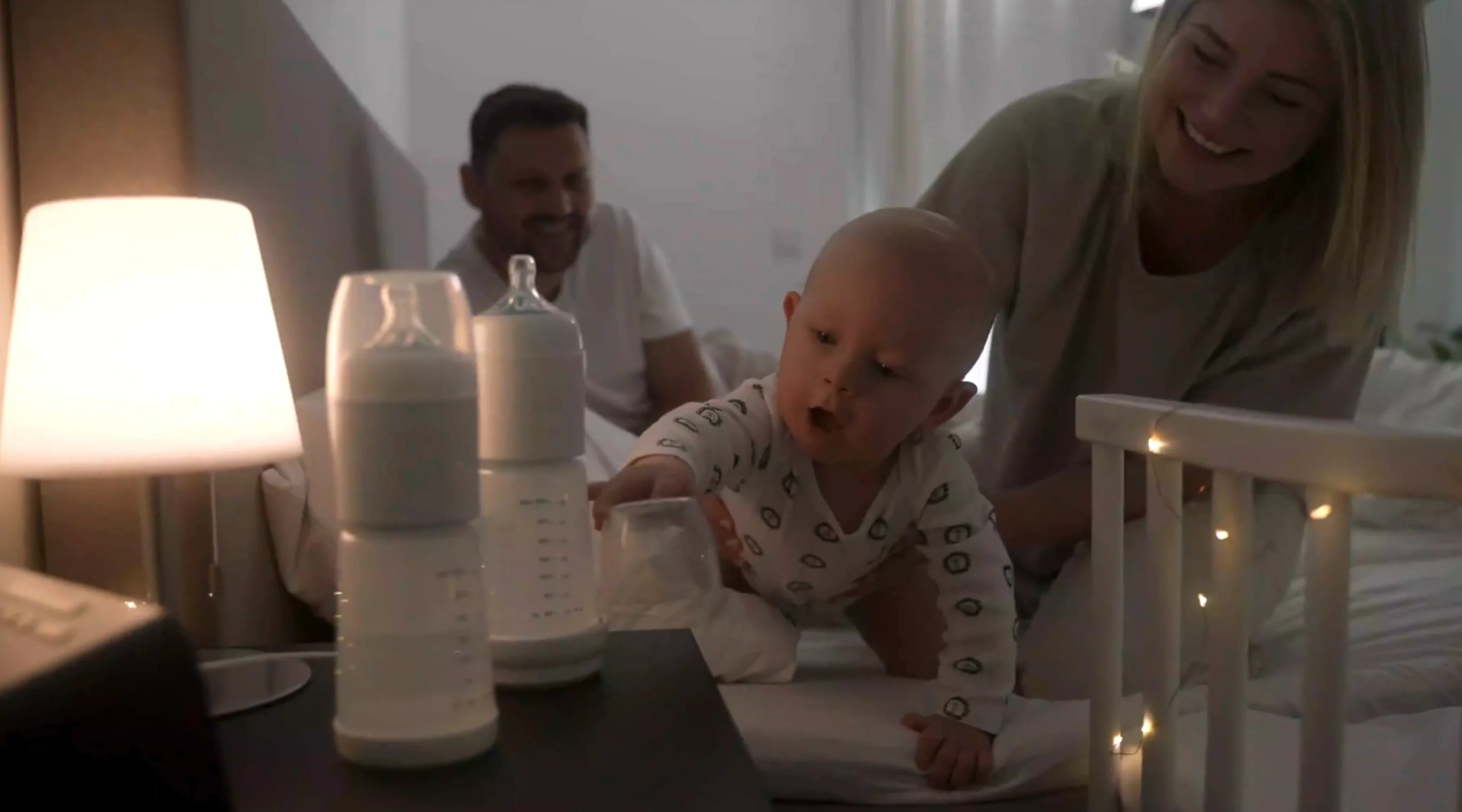 Eltern mit Baby im Bett und snoozi Nachtflaschen auf dem Nachttisch 