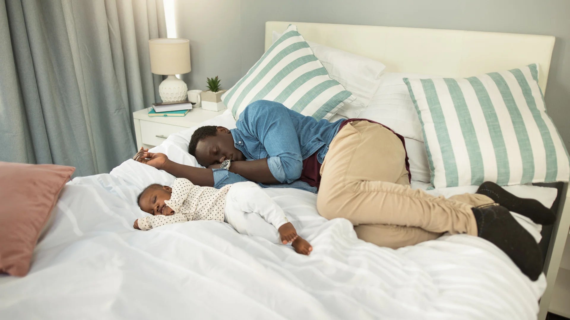 Vater und Baby liegen auf dem Bett und schlafen
