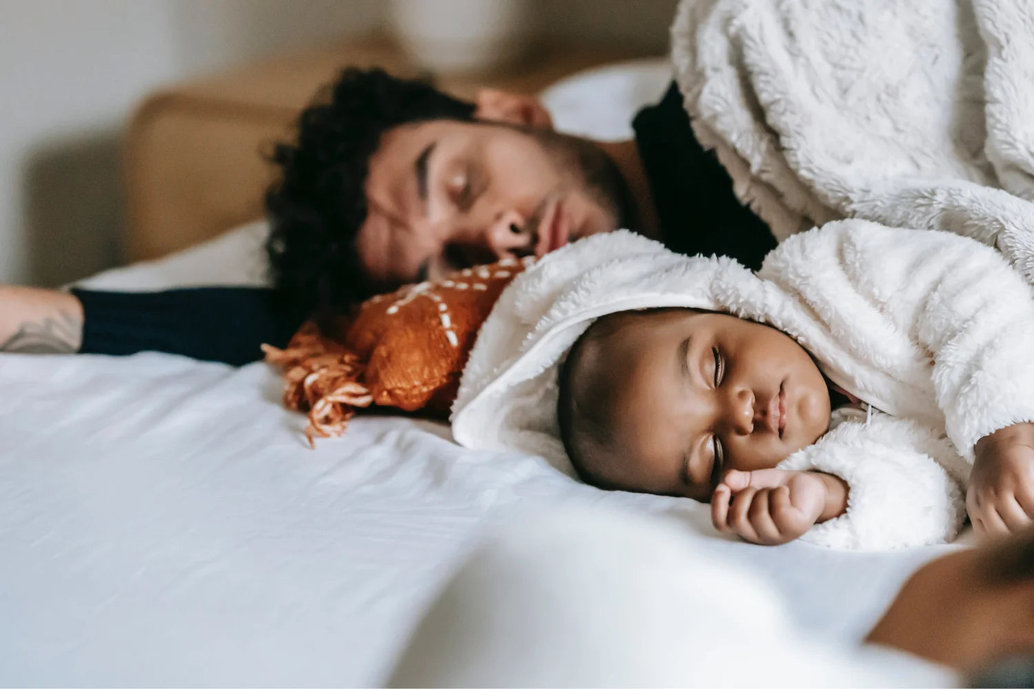 Papa und Baby liegen im Bett und schlafen entspannt 