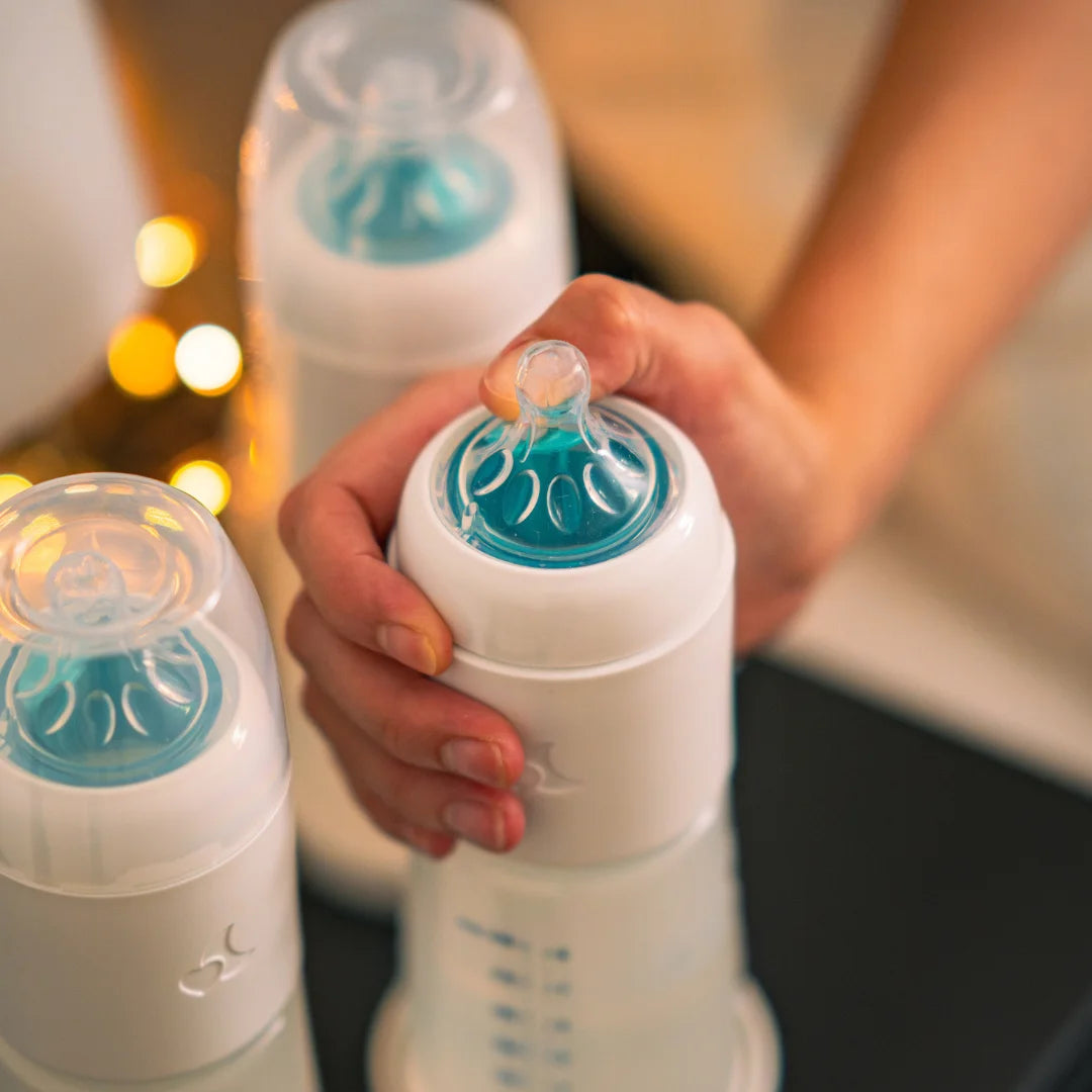 Der Öffner des Easy-Mix-System wird gedrückt um Milchpulver in die Babyflasche per Knopfdruck  zu geben 